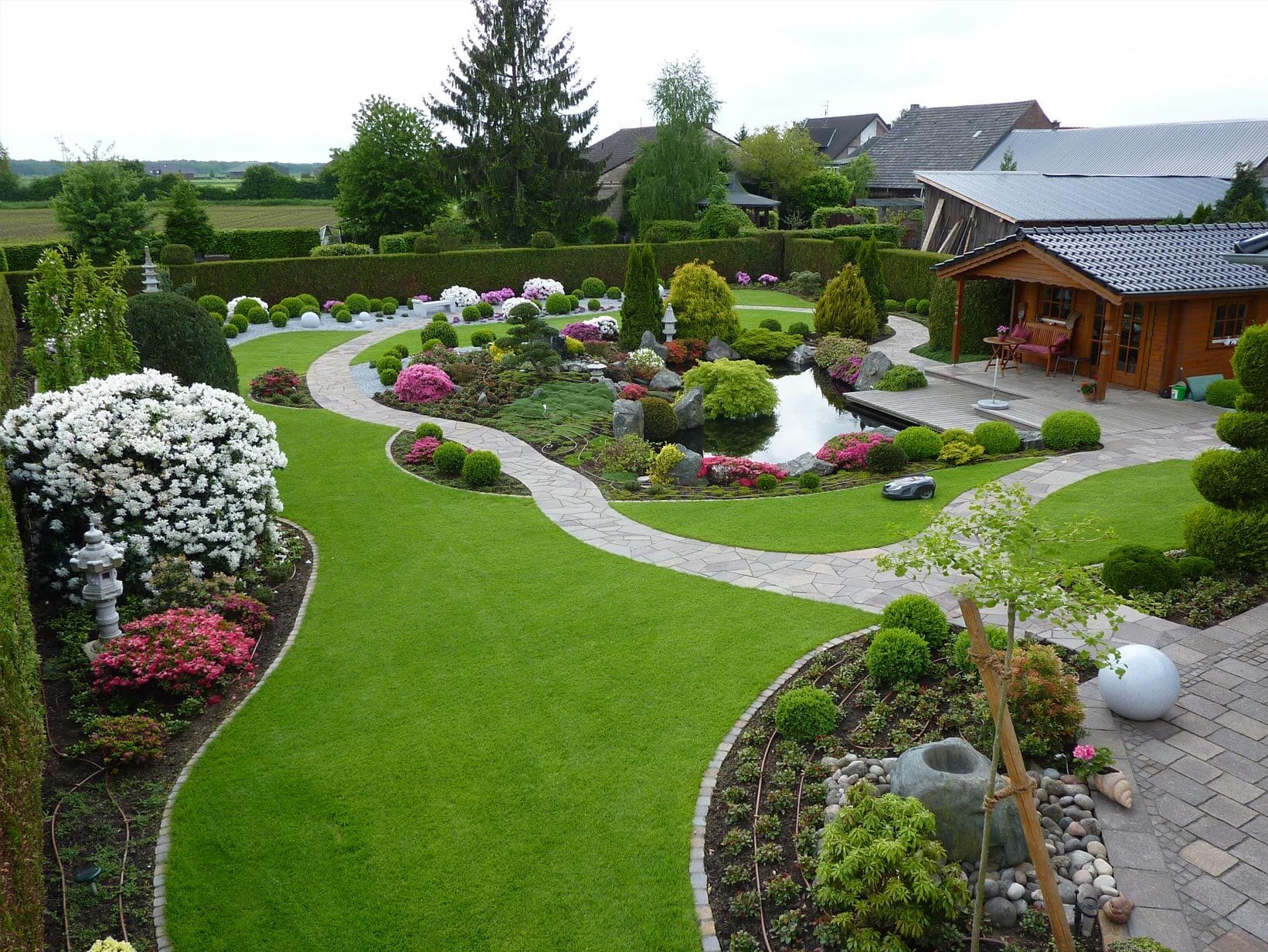 Liebevoll gestalteter Garten mit Teich, geschwungenen Wegen und gepflegten Rasenflächen, Referenzprojekt von Volksgarten38